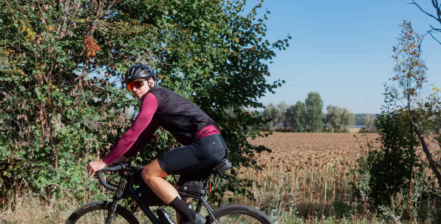 Cyclist wearing DTR cycling windbreaker on gravel road in autumn conditions — performance cycling apparel